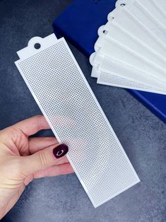 a hand holding a piece of white paper next to several blue and white papers on a table