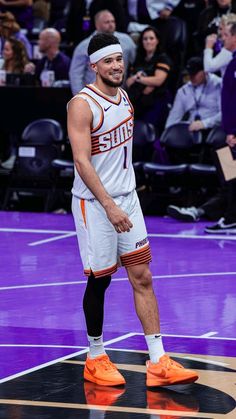 a man standing on top of a basketball court wearing an orange and white uniform with his foot in the air