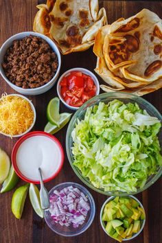 mexican food is laid out on a table with salsa, tortillas and other ingredients