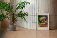 a potted plant sitting next to a painting on the wall in a room with tiled walls