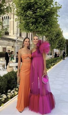 two women standing next to each other in dresses