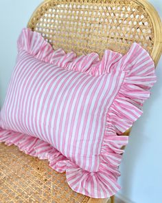 a pink and white striped pillow on a wicker chair