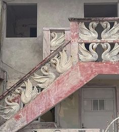 an old building with swans carved on the balconies and painted red, white and grey