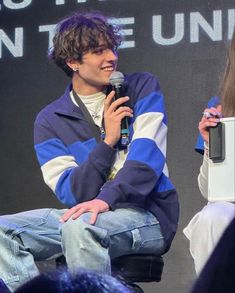 a man sitting on top of a chair holding a microphone