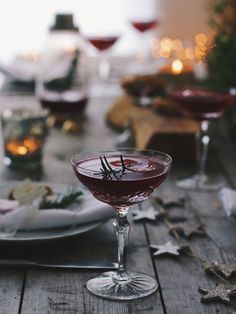 a table topped with wine glasses filled with red liquid and garnished with an olive