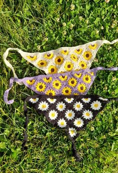 three crocheted hats sitting on top of grass with sunflowers in them