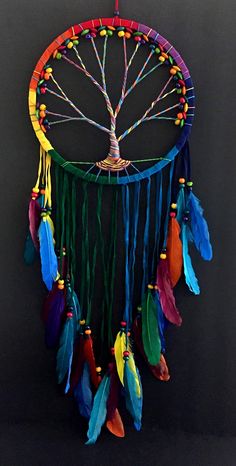 a colorful dream catcher with feathers hanging from it's side on a black background