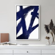 a white and blue abstract painting on a wall above a dresser