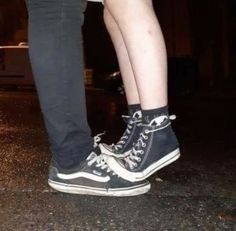 two people standing next to each other wearing black and white shoes with laces on them