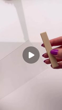 a hand holding a piece of cardboard with a video playing button on the screen in front of it