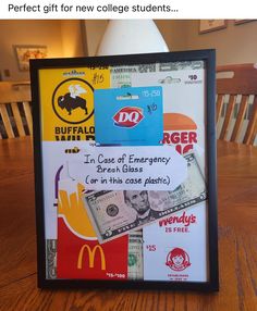 a framed sign with money on it sitting on top of a wooden table