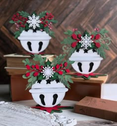 two white vases with red and green flowers on them sitting on top of books