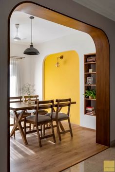 a dining room with yellow walls and wooden chairs in front of a large open doorway