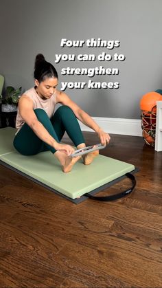 a woman is sitting on an exercise mat using her tablet