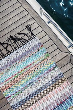 a multicolored rug sitting on top of a wooden floor next to a body of water