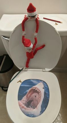 an elf is sitting on top of a toilet seat with a shark in the bowl