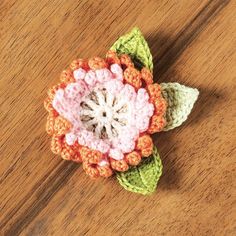 a crocheted flower sitting on top of a wooden table