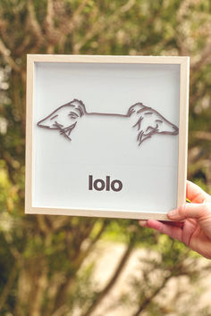 a person holding up a framed piece of artwork with the word lolo on it