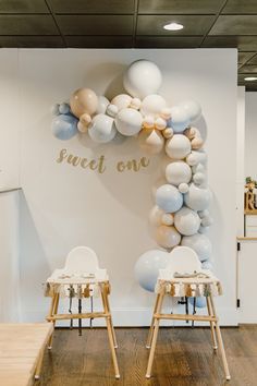 two chairs in front of a wall with balloons and the words sweet one on it