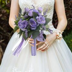 a bride holding a purple bouquet in her hands