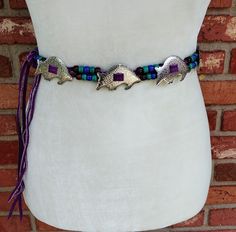 This is a vintage handmade silver metal armadillo concho belt with purple, blue and teal pony beads on purple suede cord ties. There are eleven conchos in total and it's in excellent vintage condition. Measurements: Total length 57.75 inches Adjustable from 35 to 47 inches Conchos 2.25 X 1.375 inches Price includes free shipping within the USA. Please visit my other Etsy shop for vintage jewelry: https://www.etsy.com/shop/BunnyLazuli Virtually everything we sell has been previously worn/used so Concho Belt Silver, Traditional Silver Concho Belt, Turquoise Bohemian Belt With Concho, Vintage Turquoise Belt With Concho, Adjustable Vintage Turquoise Belt, Cord Ties, Concho Belt, Purple Suede, Suede Cord