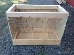 a wooden box with wire in it sitting on gravel