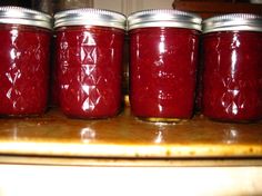 four jars filled with red liquid sitting on top of a counter