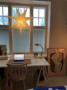 a laptop computer sitting on top of a white desk next to a star shaped light