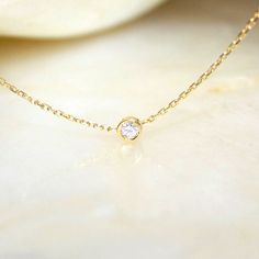 Elemental in form and timeless in meaning, our Round Diamond Bezel Necklace features a round brilliant-cut 0. 08ct natural brilliant cut diamond effortlessly balanced within a minimal gold rim.   Our signature cup bezel setting bounces light in every direction so your diamond shines as bright as you do. Each piece of jewellery is designed and handmade in our studio in London, bespoke and unique for you. It is handmade, not machine made, so it will be perfectly imperfect.  We believe in ethical, responsible and sustainable production and business practices. We only use gold from the very finest and oldest metal suppliers in Hatton Garden, the centre of the jewellery district in London which are Eco and fairtrade gold wherever possible in order to prevent any harm from the environment and to Round Diamond Necklace, Gold Bar Earrings, Minimal Gold, Bezel Necklace, Solitaire Necklace, Diamonds And Pearls, Solid Gold Necklace, Diamond Solitaire Necklace, Solitaire Necklaces