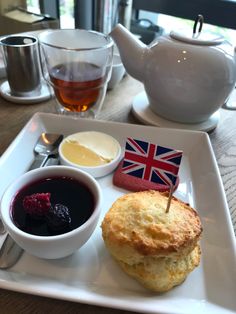 a white plate topped with food next to two cups of tea and sauces on a table