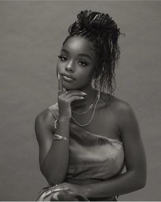 a black and white photo of a woman with her hand on her chin looking at the camera