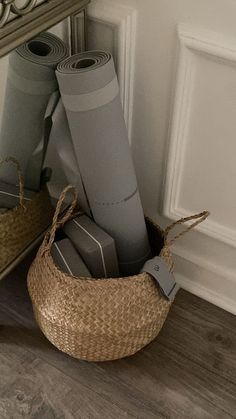 a basket filled with rolls of paper sitting on top of a wooden floor next to a mirror