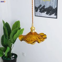 a lamp hanging from a ceiling next to a potted plant