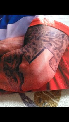 a man's arm with tattoos on it and an american flag in the background