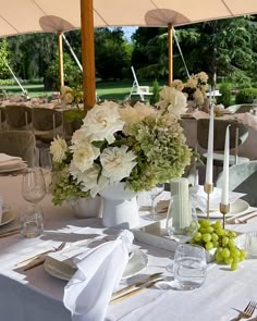 the table is set with white and green flowers in vases, silverware, forks, napkins, and wine glasses