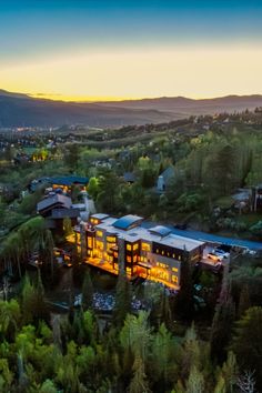 an aerial view of a large building in the middle of some trees and mountains at sunset