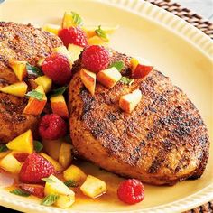 two pork chops with fruit salad on a yellow plate