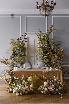 an arrangement of flowers on a table with a chandelier