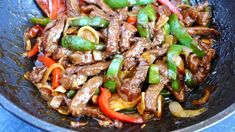 stir fry with beef, peppers and onions in a wok