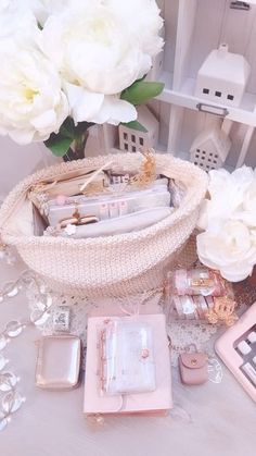 a table topped with lots of pink and white flowers next to a basket filled with personal items