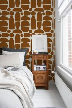 a bed sitting under a window next to a wall with brown and white designs on it