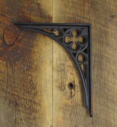 an iron shelf bracket on the side of a wooden wall with wood grained flooring