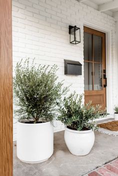 two white planters sitting on top of a porch next to a brick building with the words spring porch inspiration