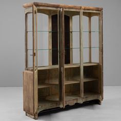 an old wooden cabinet with glass doors and shelves on the front, against a gray background