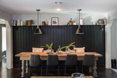 a dining room table and chairs with plants on the wall