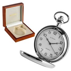 an open pocket watch with a wedding ring in it and a wooden box on the side