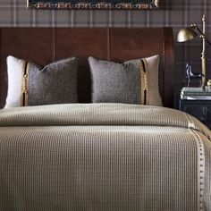 a bed with two pillows on top of it and a painting above the headboard