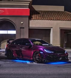 a purple car is parked in front of a gas station with blue lights on it