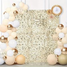 a gold and white party backdrop with balloons