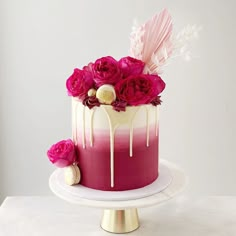 a pink and white ombrella cake with flowers on the top is sitting on a plate